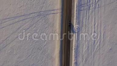 鸟瞰雪域和道路.. 越野车在冬天的道路上行驶，穿过雪地。 汽车的鸟瞰图